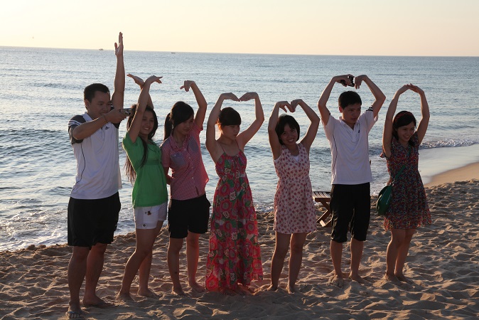 A group of people standing on a beach posing for the cameraDescription automatically generated